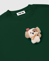 Close-up of dimensional plush puppy with brown eye patch and pink beret on STICKYZOO green sweatshirt