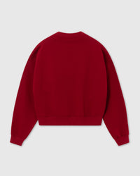 Styled shot of red Saint Teddy Bear Sweatshirt on neutral background