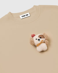 Macro close-up of hand-stitched plush puppy showing dimensional sherpa texture, brown eye patch, and embroidered nose