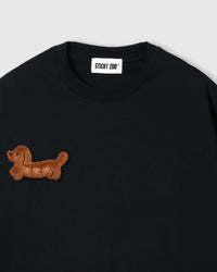 Close-up of plush dachshund applique on black cotton showing brown fur texture and 3D dimension