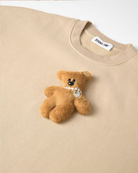 Detail of hand-stitched teddy bear applique on STICKYZOO cream sweatshirt showing dimensional craft