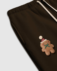 Detail shot of hand-stitched gingerbread character with green bow on dark brown heavyweight cotton fleece