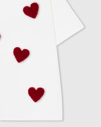 Styled view of white Scattered Heart T-Shirt showing contrast between red plush and white cotton