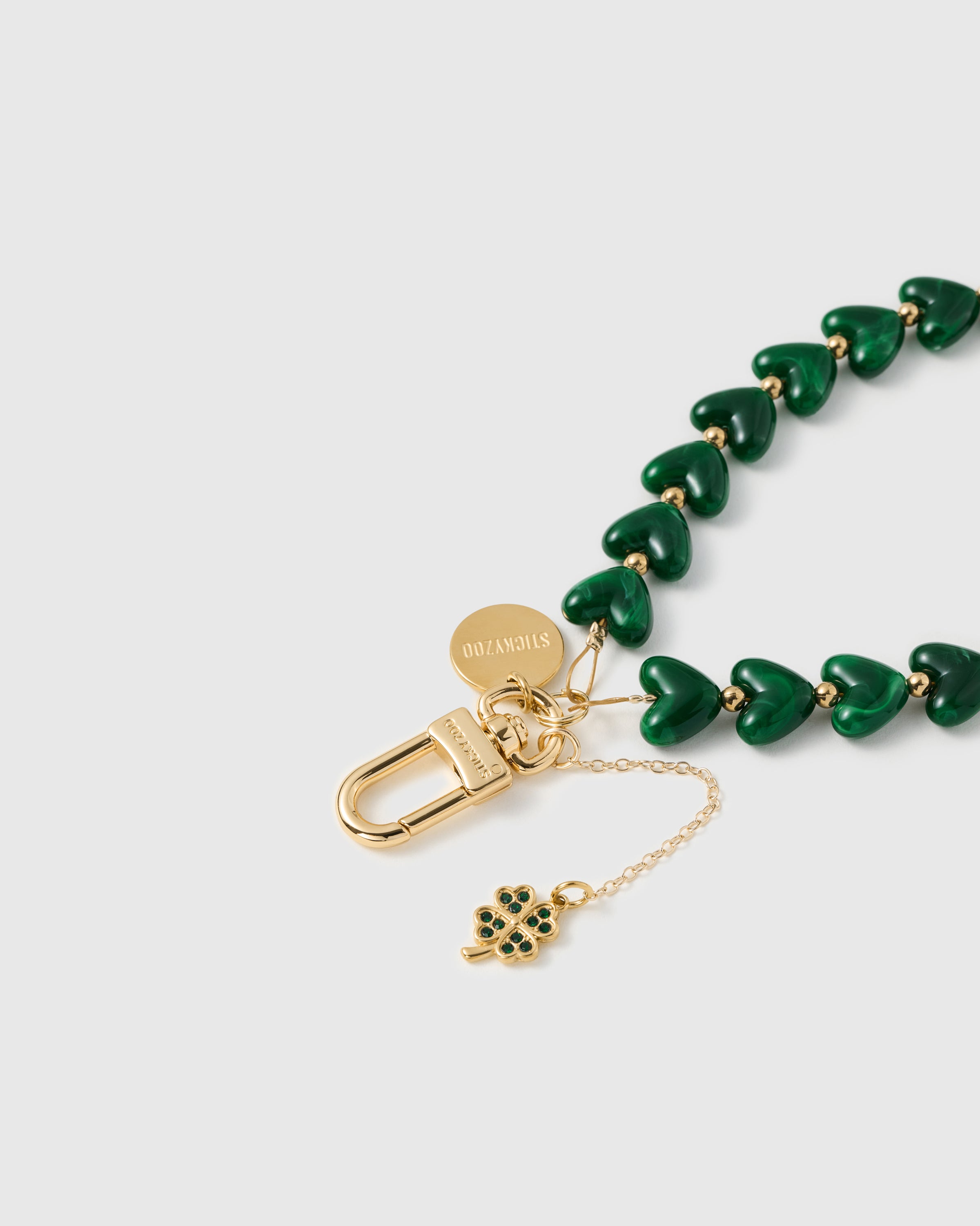 18K GOLD-PLATED HARDWARE — Close-up of engraved STICKYZOO disc and gold carabiner with emerald heart beads — Best Seller