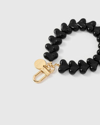 Close-up of gold-plated clasp and engraved STICKYZOO charm disc with black heart beads