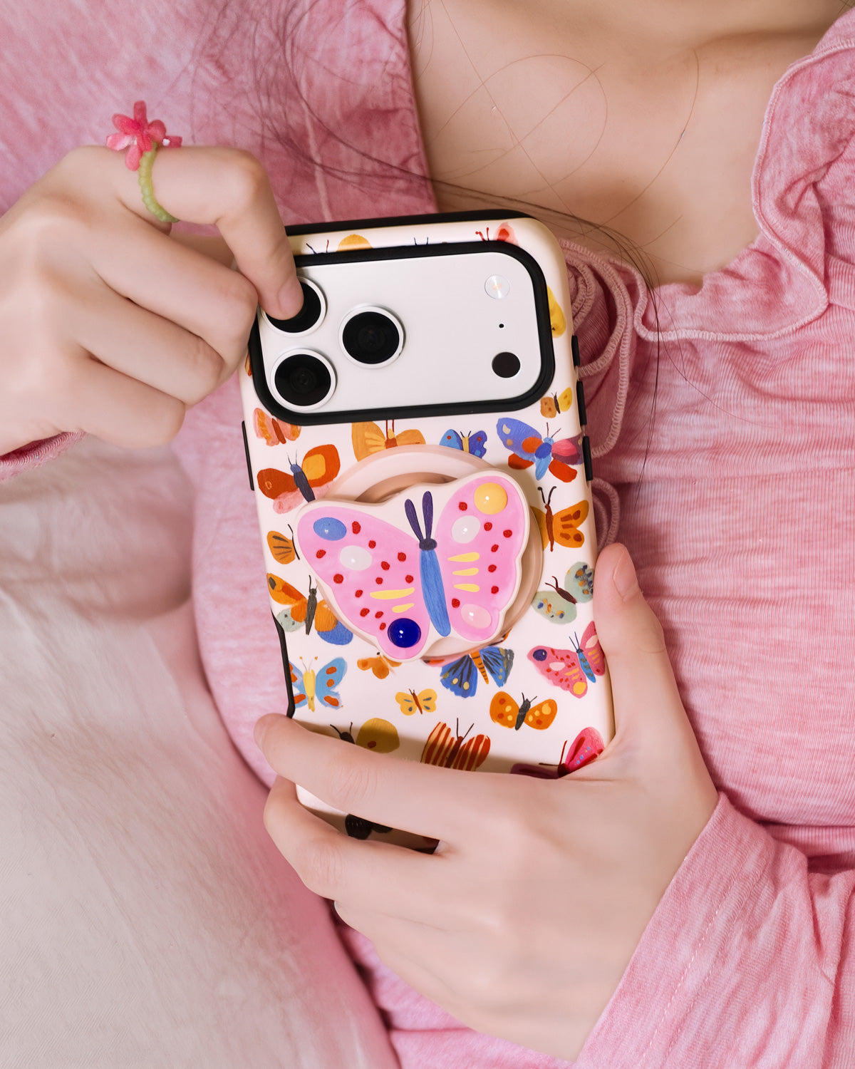 Painted butterfly phone case held in hand with the retractable MagSafe grip popped out from the back