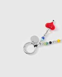 Close-up of silver-tone ring clasp and engraved charm disc with red heart and colorful beads