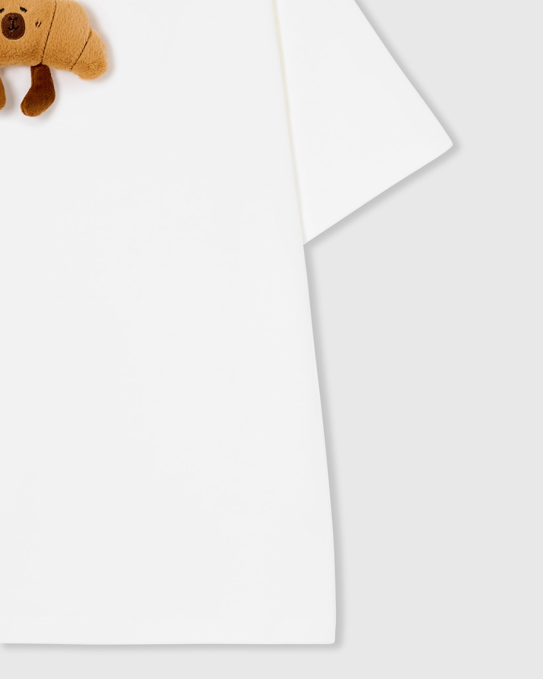Detail of hem and fabric on STICKYZOO white Runaway Croissant T-Shirt showing premium cotton weight