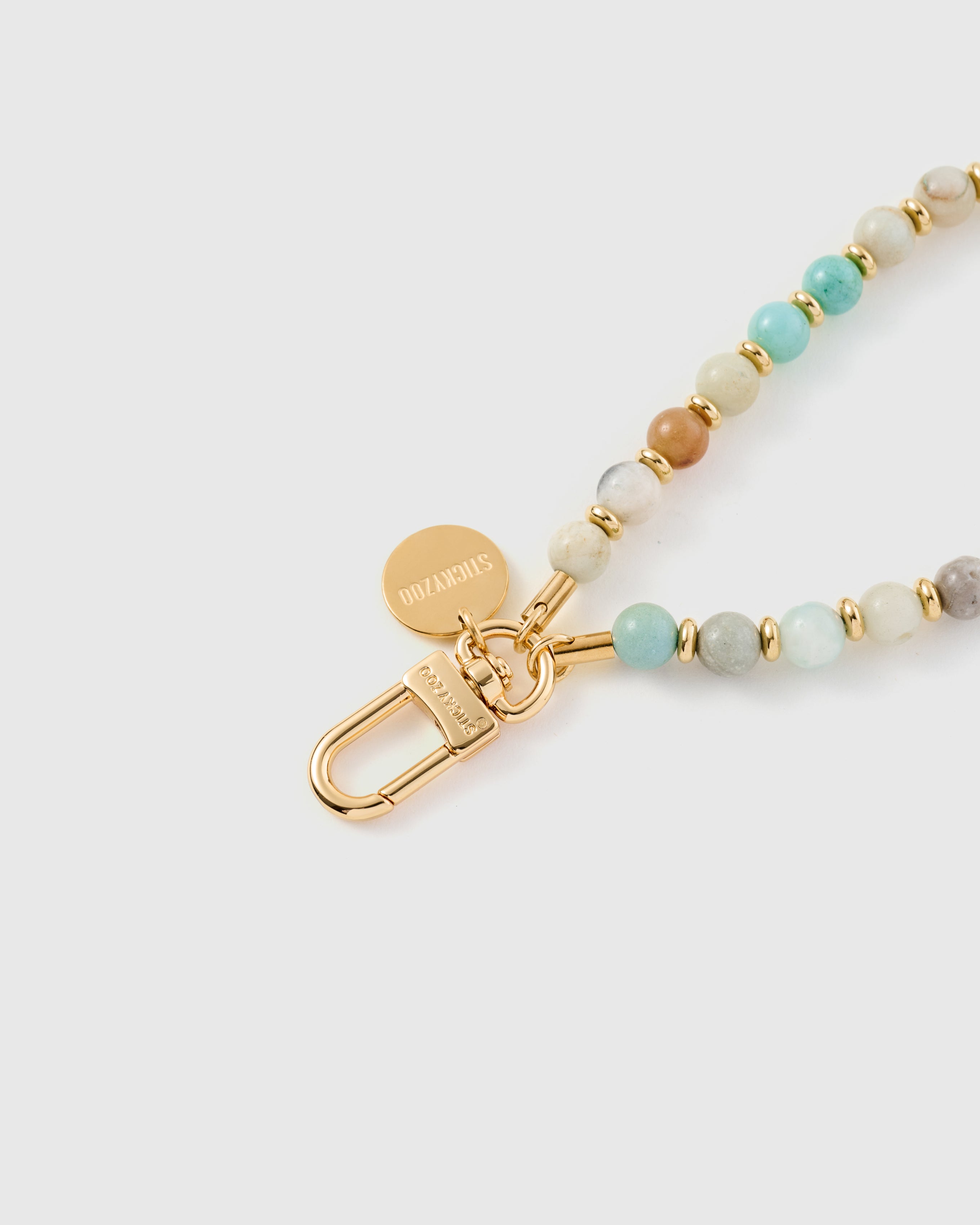 {{18K gold-plated hook}} Close-up of gold-plated clasp and engraved STICKYZOO charm disc with amazonite beads