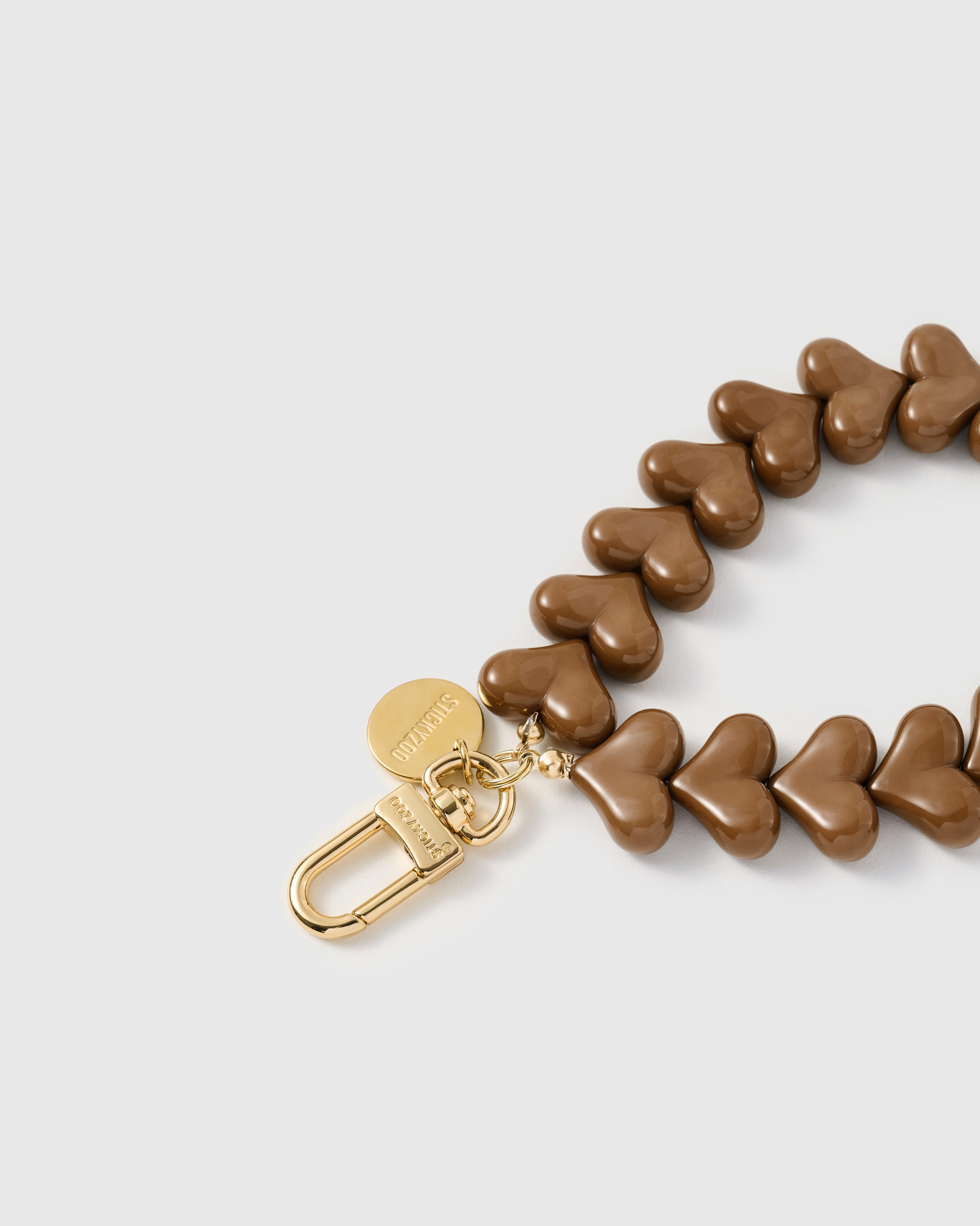 Close-up of 18K gold-plated carabiner and engraved disc with glossy butterscotch heart beads — STICKYZOO