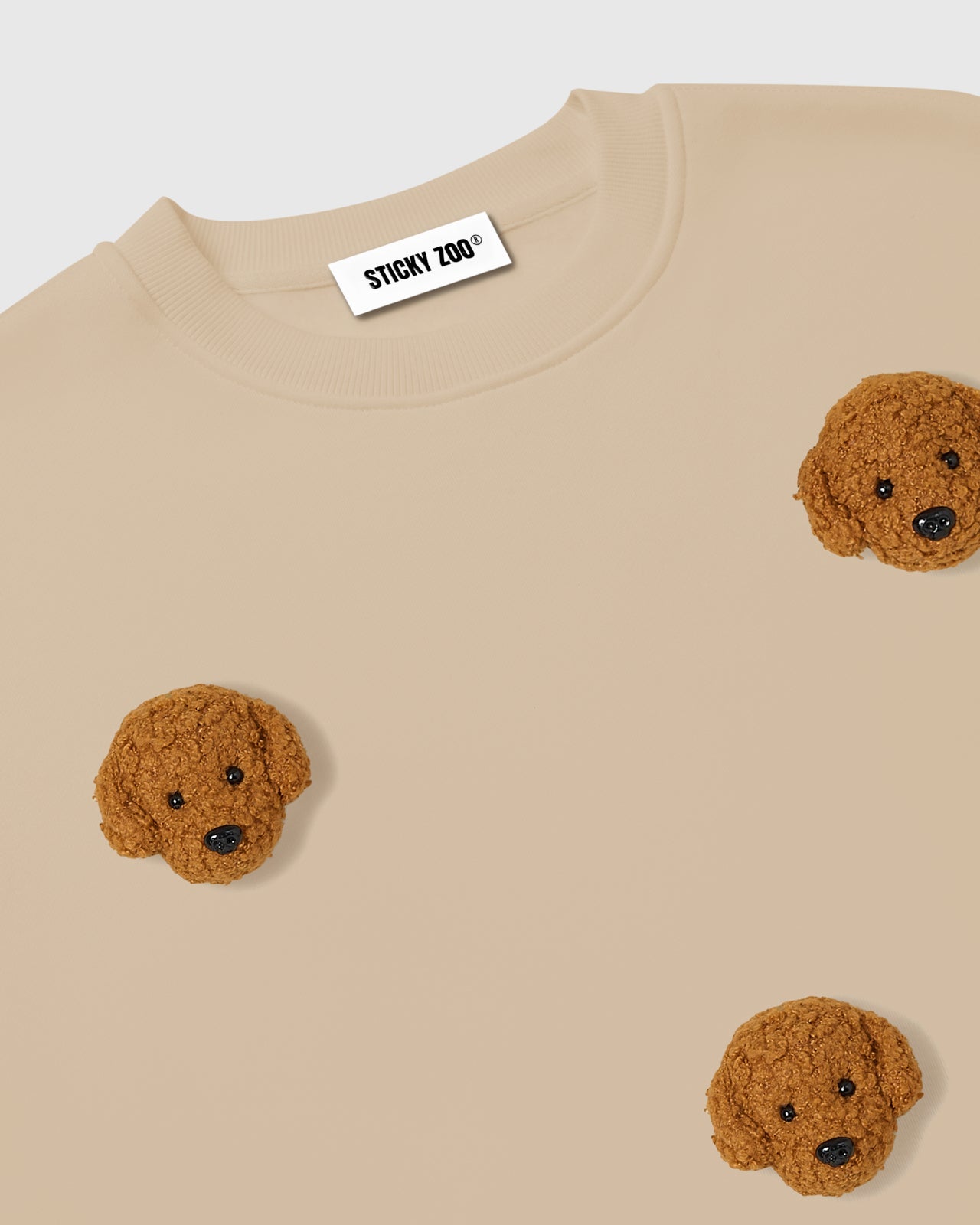 Back view of STICKYZOO Poodle Parade Sweatshirt in beige showing ribbed cuffs and oversized cut