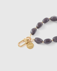 Close-up of gold-plated clasp and engraved STICKYZOO charm disc with storm grey agate beads
