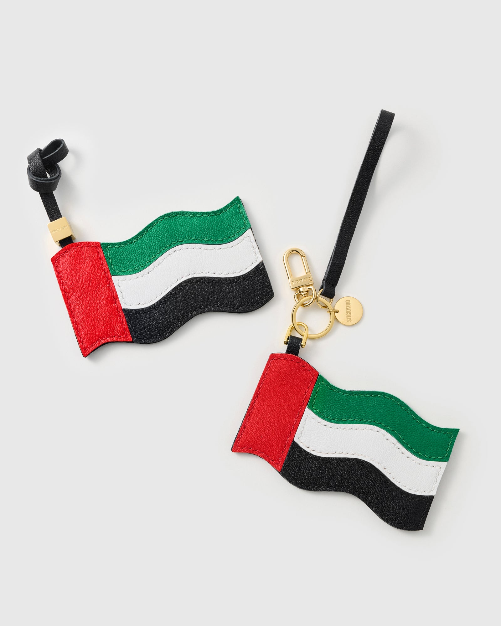Both UAE flag charm attachment styles — leather strap loop and 18K gold-plated keychain clip with STICKYZOO coin