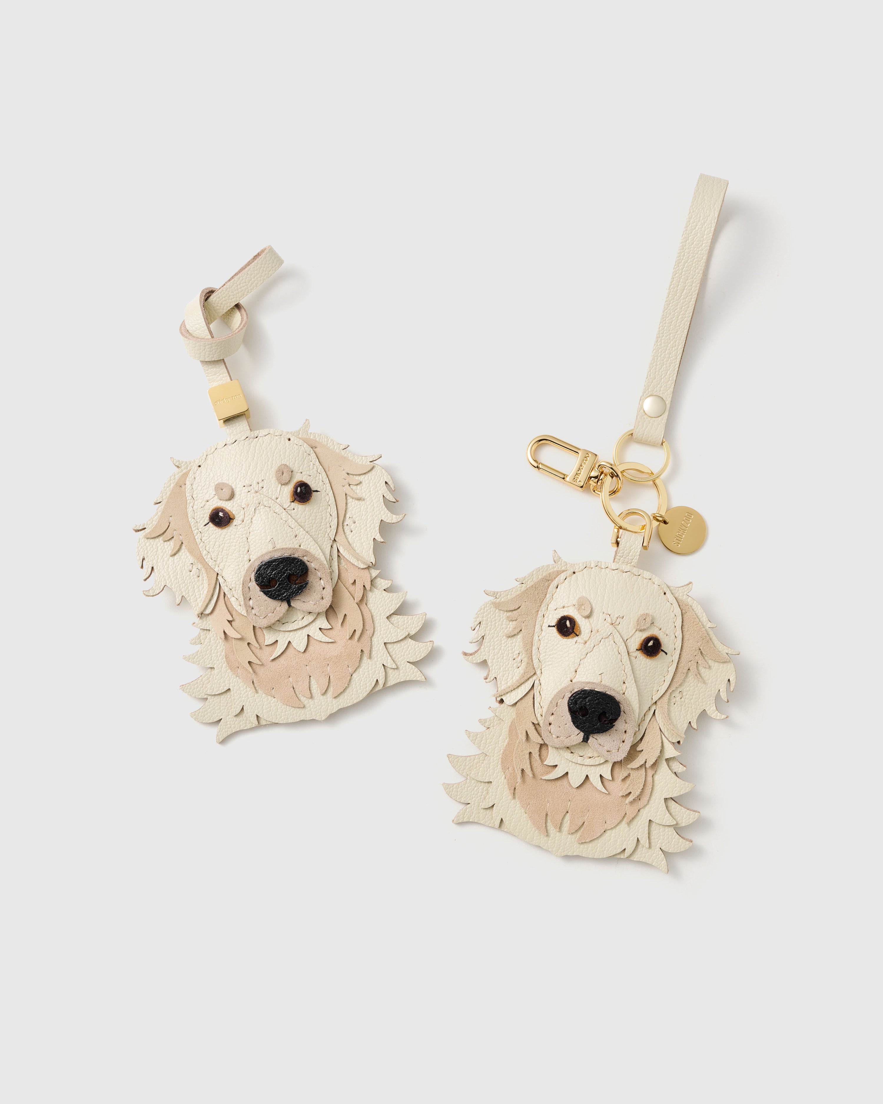 {{Dual attachment.}} Both editions of the Golden Retriever charm — leather strap loop for bags, or 18K gold-plated keychain clip with engraved STICKYZOO disc.