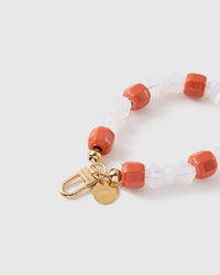 Close-up of the 18K gold-plated hook, engraved STICKYZOO disc and clementine-orange and frosted beads — every one different