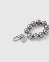 Close-up of the silver-tone hook, engraved STICKYZOO disc and grey pearl-style beads — soft even sheen