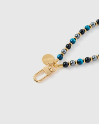 Close-up of gold-plated clasp and engraved STICKYZOO charm disc with mixed blue and black stone beads