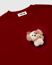Close-up of 3D plush puppy with brown eye patch and floppy tan ears on STICKYZOO red sweatshirt