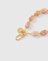 Close-up of gold-plated clasp and engraved STICKYZOO charm disc with blush marble nugget beads