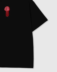 Faceted glass-bead jellyfish tentacles hanging free off the appliqué near the dropped shoulder seam of the black tee