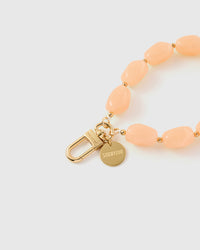 Close-up of gold-plated clasp and engraved STICKYZOO charm disc with peach stone beads