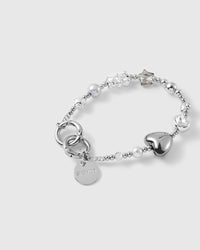 Close-up of the glossy silver puff heart, bezel-set faceted clear bead, grey pearl-effect bead and stardust silver bead with engraved STICKYZOO disc