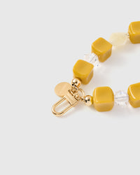 Close-up of 18K gold-plated clasp and engraved charm disc with saffron cube beads