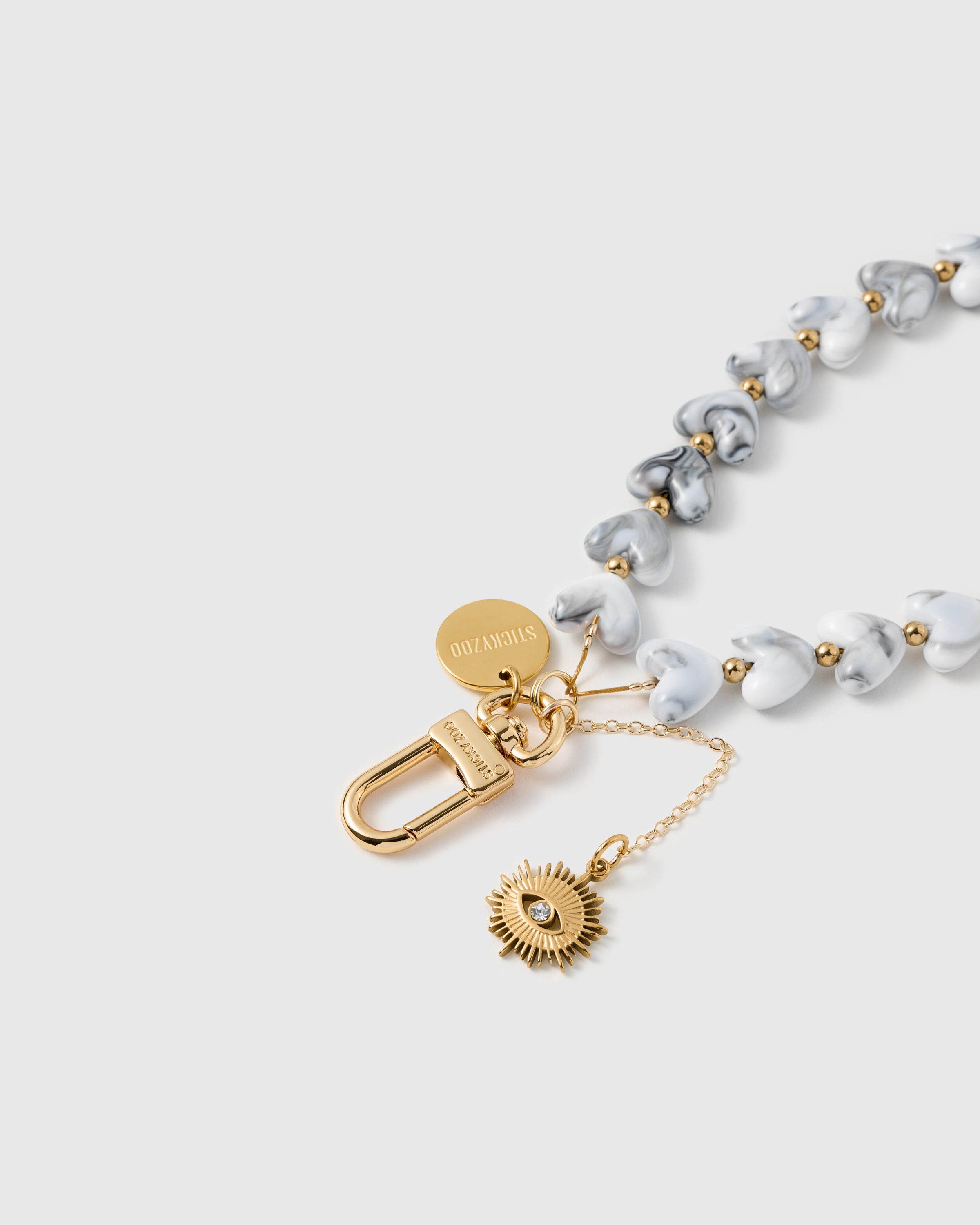 Close-up of 18K gold-plated lobster clasp and engraved STICKYZOO charm disc