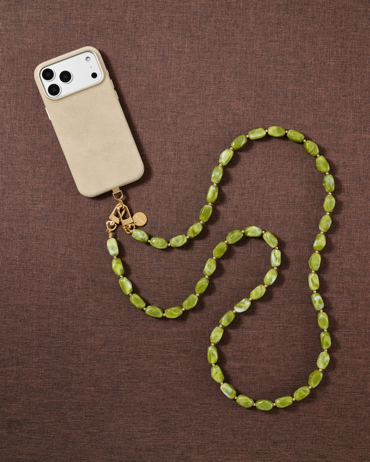 Moss olive-green handmade beaded cross-body phone strap styled on a fabric flat-lay, showing the polished resin beads and gold hardware