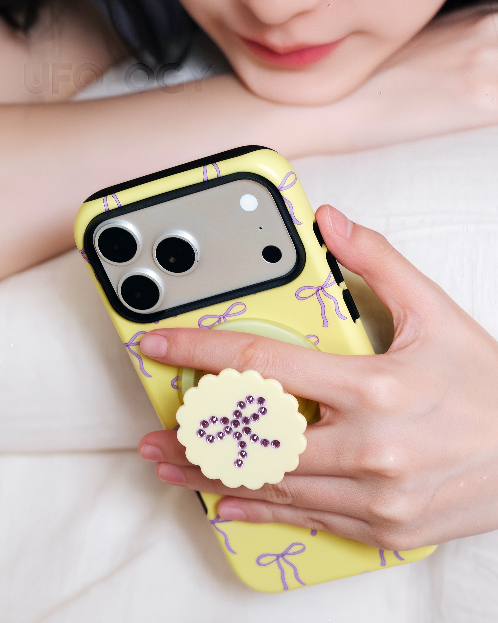 Fingers gripping the retractable MagSafe pop-grip on the back of the butter bow phone case