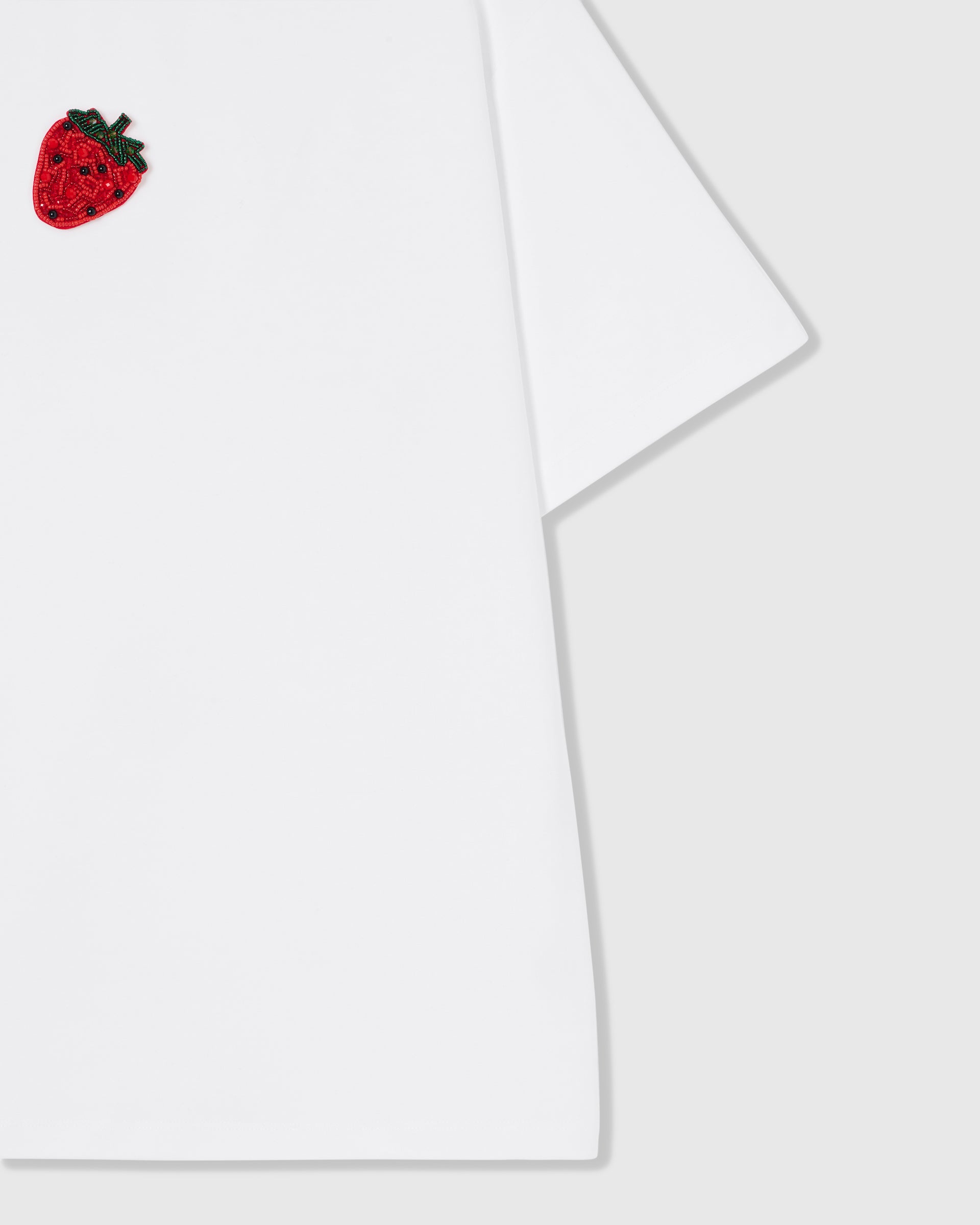 Macro of 230gsm cool-touch cotton and folded sleeve with the hand-beaded glass strawberry detail on the STICKYZOO tee