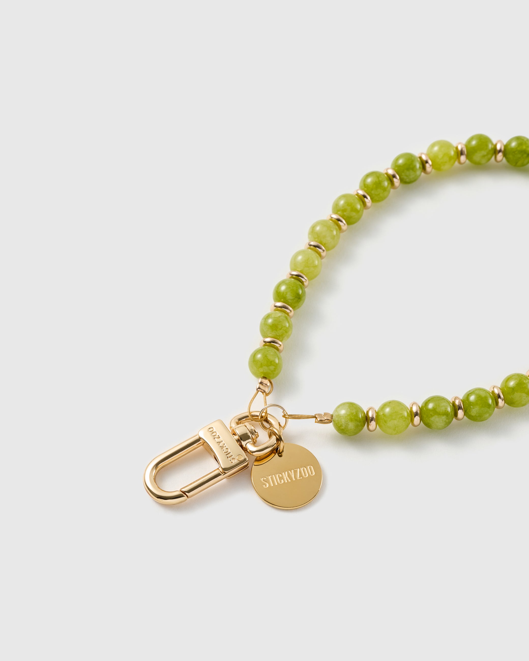 Macro of the 18K gold-plated clasp and engraved STICKYZOO charm disc on the stone bead strap