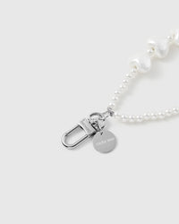 Pearl heart phone strap hanging from phone showing wrist-carry functionality