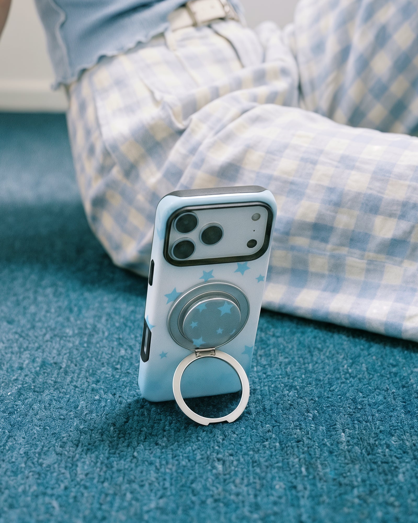 Sky-star phone case propped upright on a surface with the metal ring kickstand swung open