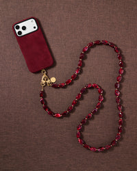 Garnet beaded cross-body phone strap styled on fabric, handmade not factory