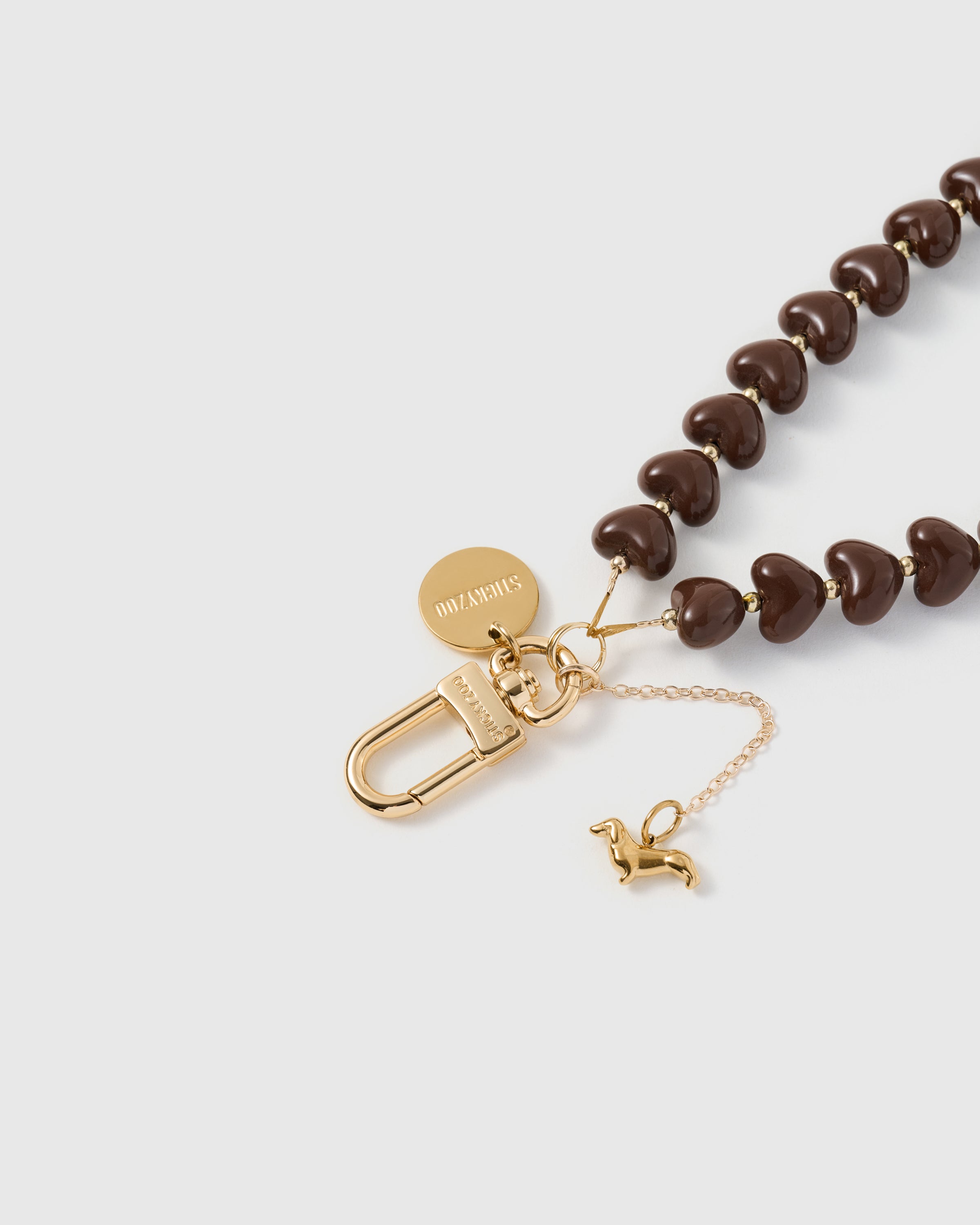 Close-up of the gold-plated carabiner and engraved STICKYZOO disc on the cocoa dachshund heart phone strap. Loved by Thousands.