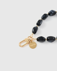Close-up of gold-plated clasp and engraved STICKYZOO charm disc with dark marble beads