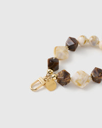 Close-up of the 18K gold-plated hook, engraved STICKYZOO disc and mocha marbled beads — no two swirls alike