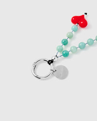 Close-up of silver ring connector and engraved charm disc with jade stone beads and red heart