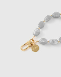 Close-up of gold-plated clasp and engraved STICKYZOO charm disc with grey marble nugget beads