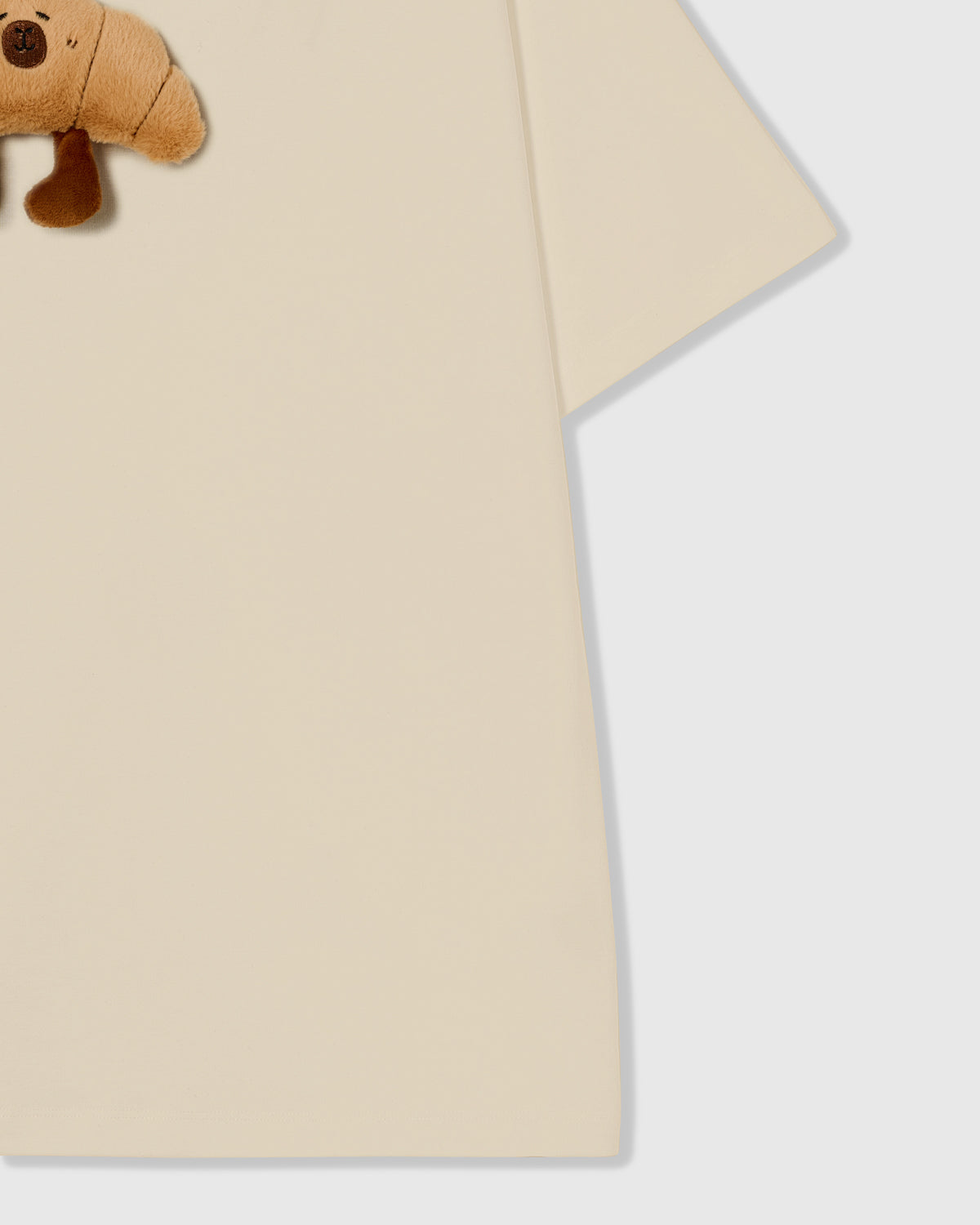 {{Kept by 99% of buyers}} Detail of hem and fabric on STICKYZOO beige Runaway Croissant T-Shirt showing premium cotton weight