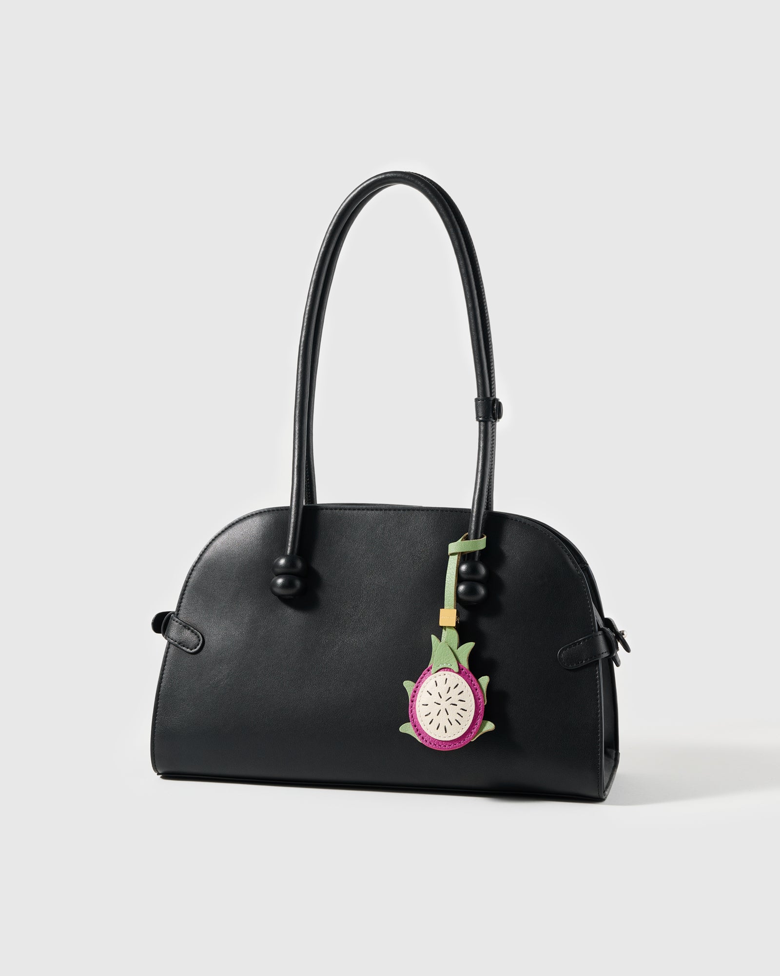 STICKYZOO dragon fruit leather charm on a black top-handle bag showing scale, styling, and bright tropical color contrast