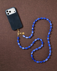 Cobalt-blue handmade beaded cross-body phone strap styled flat on fabric