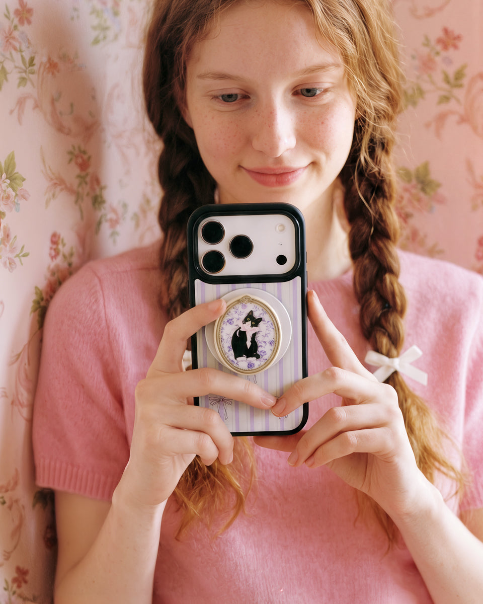 Fingers gripping the popped-out retractable MagSafe pop-grip on the back of the tuxedo cat phone case