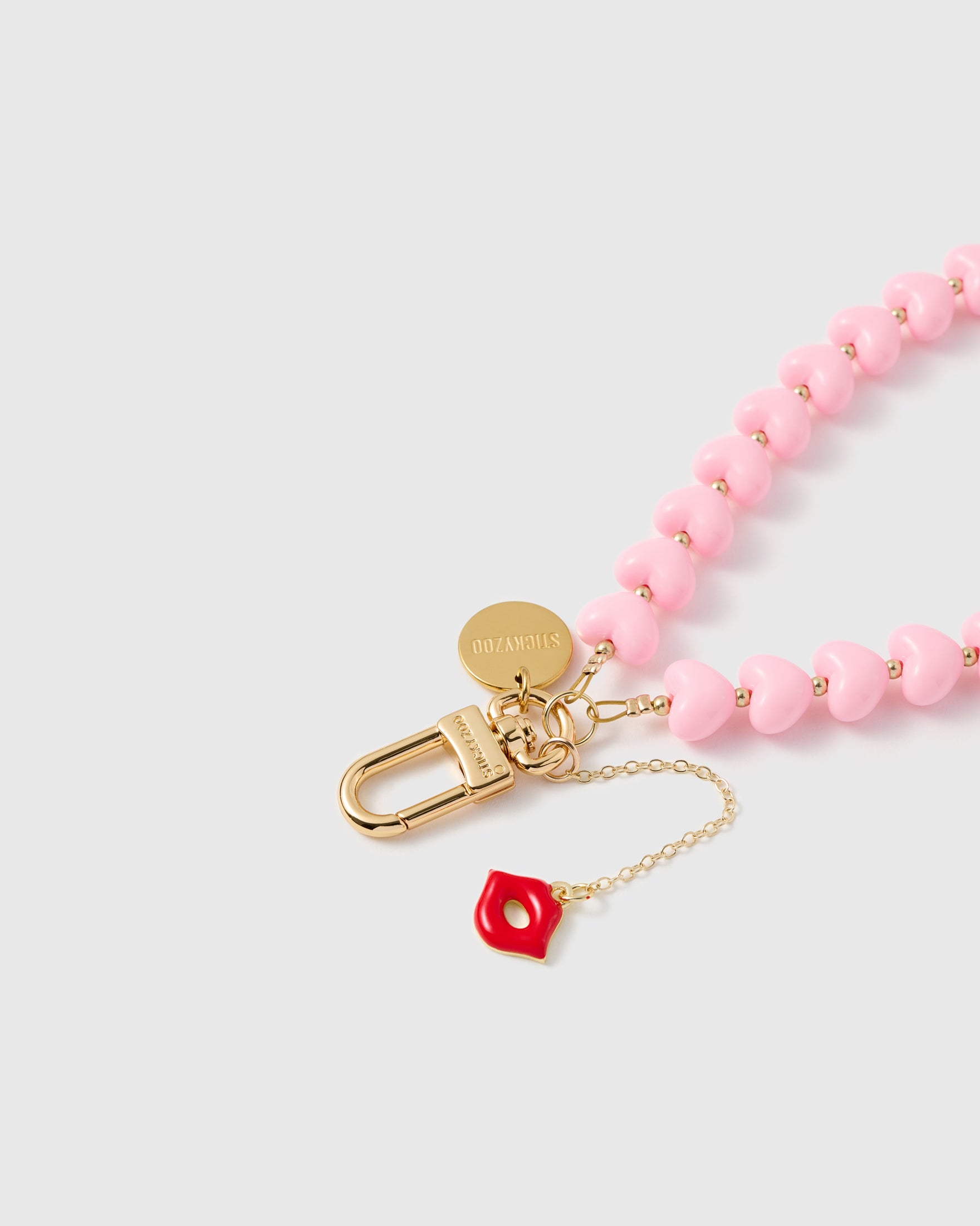 Close-up of 18K gold-plated lobster clasp and engraved STICKYZOO charm disc