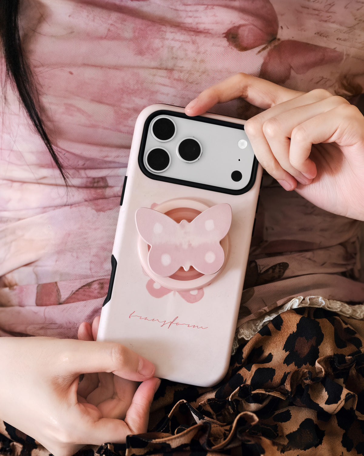 Two hands holding the pearl butterfly phone case with the 3D pearlescent butterfly grip catching the light
