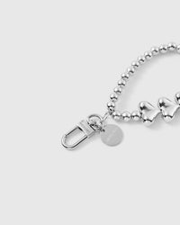 Silver heart phone strap hanging from phone showing wrist-carry functionality