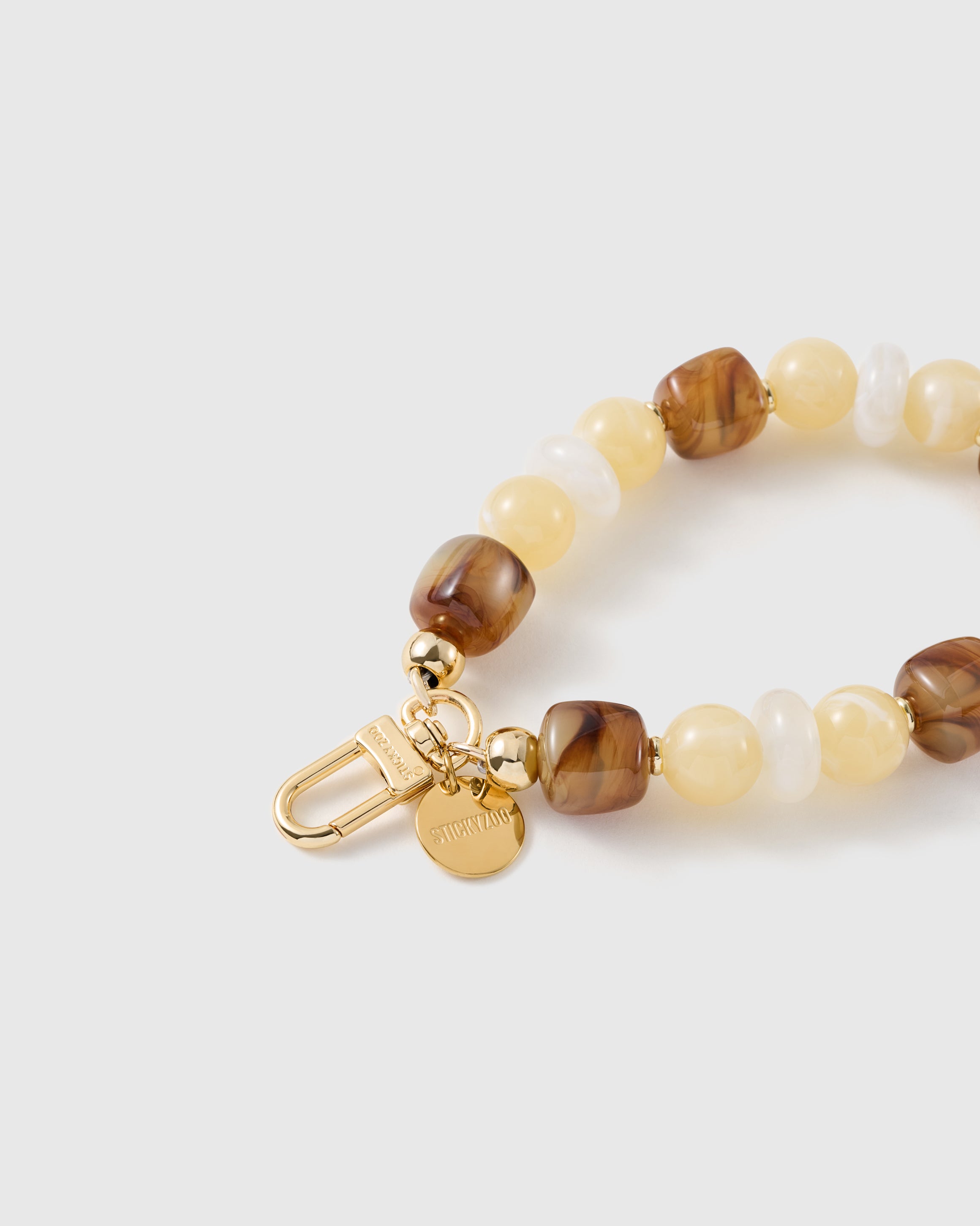 Close-up of the 18K gold-plated hook, engraved STICKYZOO disc and honey marbled beads — no two alike