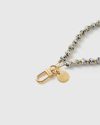 Close-up of the 18K gold-plated hook, engraved STICKYZOO disc and cream speckled stone beads — each one unique