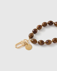 Close-up of the 18K gold-plated hook, engraved STICKYZOO disc and the swirled amber-brown beads — no two swirls alike